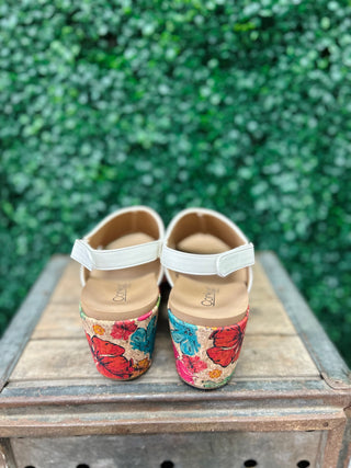 Corky's Carley floral wedge sandals with white straps displayed on wooden surface outdoors