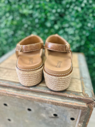 Corky's wedge sandals with woven platform sole and ankle strap, displayed on rustic metal box.