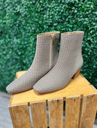 Corky's houndstooth patterned ankle boots with block heels displayed on wooden crate against green backdrop.