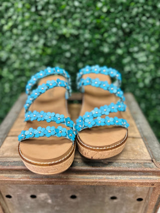 Corky's wedge sandals with blue floral straps and cork soles on wooden surface