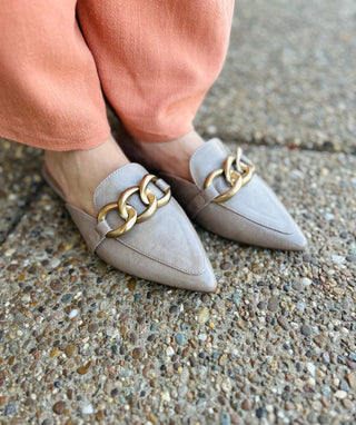 Woman wearing Corky's Playin For Keeps pointed toe mules with gold chain detail on concrete surface.