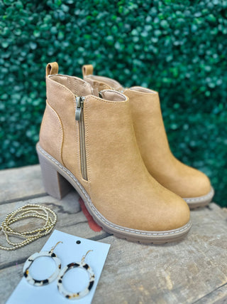 Camel ankle boots with side zipper and block heel displayed with accessories on stone surface