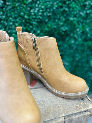 Tan leather ankle boots with side zippers and block heels displayed on wooden surface