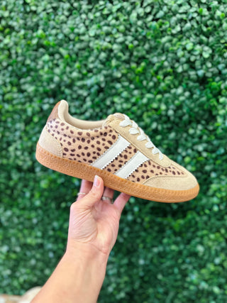 Corkys Heads Up Sneaker with leopard print upper, white stripes, and gum sole held up outdoors.