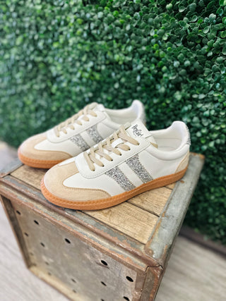 Corkys Heads Up Sneaker with silver glitter stripes, cream leather upper, and gum sole displayed outdoors.