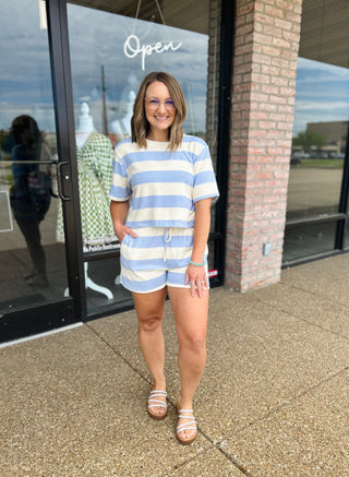 Woman wearing a striped matching shorts and top set with sandals outside a boutique.