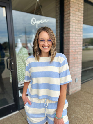 Woman wearing a striped matching short sleeve top and drawstring shorts set outside boutique.