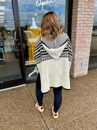Woman wearing a Ganz Cozy Contrast Hooded Wrap with Aztec pattern, paired with leggings.