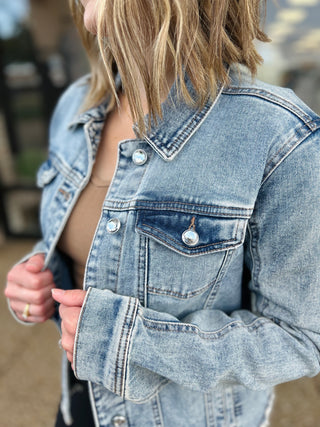 Woman wearing light blue denim jacket with crystal buttons and distressed details from Pine Apparel