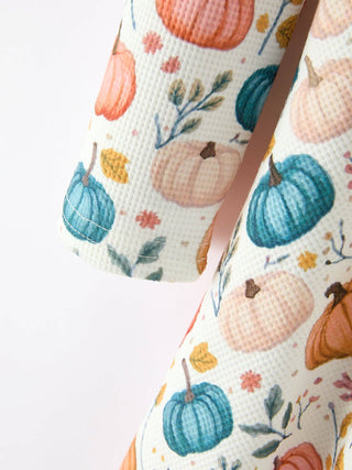 Close-up of a girls' dress featuring a colorful pumpkin and floral autumn print pattern.
