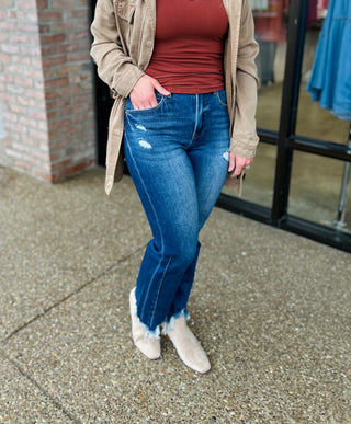 Woman wearing distressed high-rise cropped straight jeans with frayed hem, paired with beige jacket and boots.