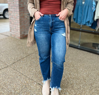 Woman wearing distressed high-rise cropped straight jeans with frayed hem and ripped details.
