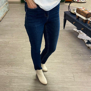 Woman wearing dark denim slim straight jeans with beige ankle boots standing on wood floor