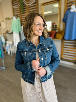 Woman wearing dark blue denim jacket with silver buttons in clothing store setting