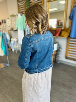 Woman wearing Risen Dark Tide Denim Jacket with light skirt, shown from behind in retail store.