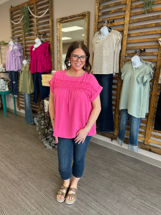 Woman wearing dark wash denim capri jeans with side slits in a boutique clothing store setting.