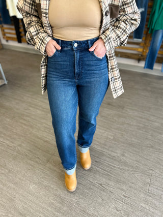 Woman wearing high-rise straight leg dark wash jeans with cuffed hems and tan boots
