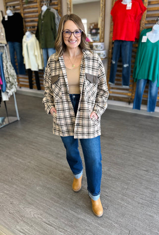 Woman wearing dark wash cuffed high-rise straight jeans with plaid jacket and brown boots in clothing store.