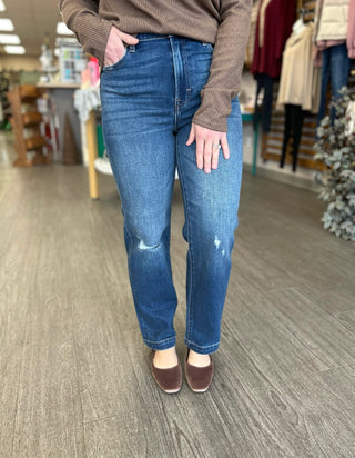 Person wearing distressed cropped straight leg jeans with brown sweater and shoes in retail store