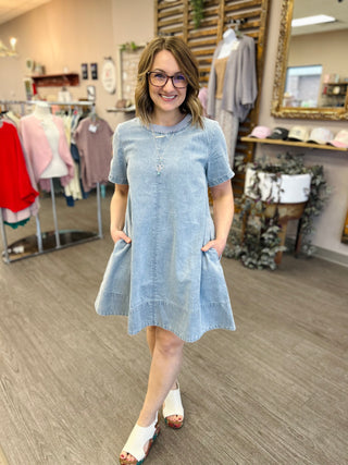 Woman wearing light blue denim short-sleeve dress with pockets in clothing boutique store