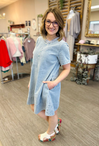 Woman wearing light blue denim short-sleeve dress with pockets in clothing boutique store