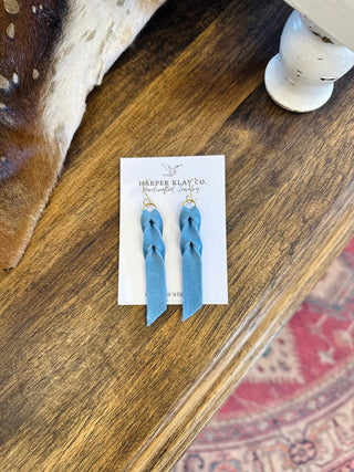 Harper Klay Co handcrafted denim earrings displayed on white card against wooden surface with cowhide rug.