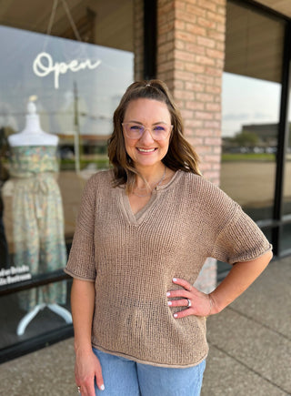Woman wearing a relaxed V-neck crochet knit short sleeve top paired with jeans.