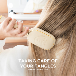 Woman using tan detangler hair brush on blonde hair in bright bathroom setting