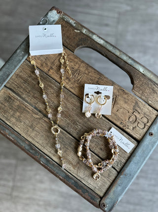 Simply Noelle jewelry set featuring beaded necklace, hoop earrings, and stretch bracelet on rustic wood crate.