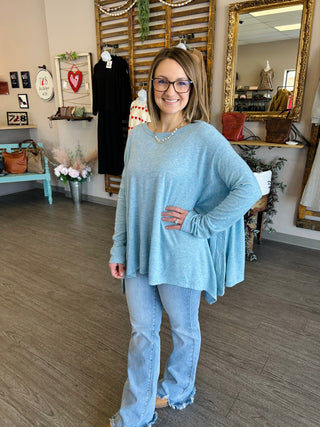 Woman wearing light blue oversized sweater and jeans in boutique clothing store setting