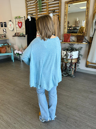 Woman wearing blue oversized top and jeans in boutique store setting
