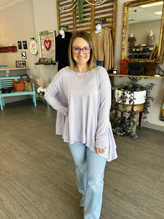 Woman wearing relaxed lavender long-sleeve top with light wash jeans in boutique setting