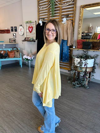 Woman wearing yellow flowing top with jeans in boutique store setting
