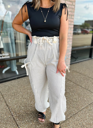 Woman wearing VERY J Elevated Ease Striped Joggers with drawstring waist and tie pockets, paired with black top.