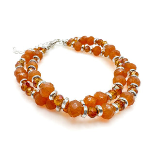 Orange gemstone beaded bracelet with silver spacers and lobster clasp closure on white background.
