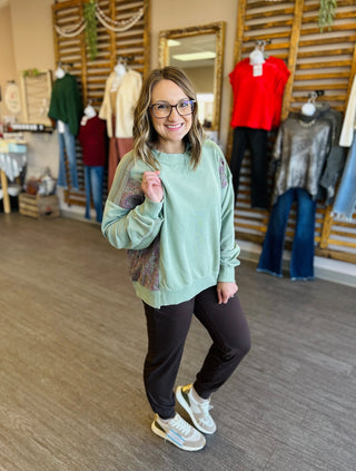 Woman wearing mint green sweatshirt and dark joggers in casual clothing boutique setting
