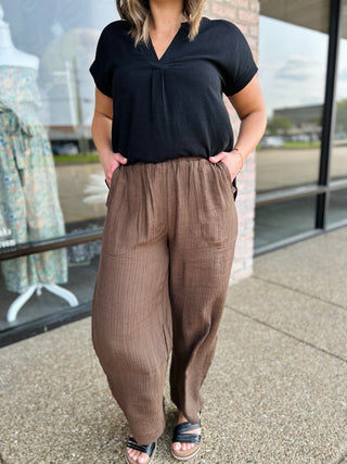 Woman wearing wide-leg linen blend pocket pants paired with a black v-neck top and sandals.