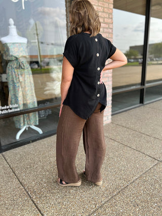 Woman wearing wide-leg linen pocket pants paired with a black button-back top outdoors.