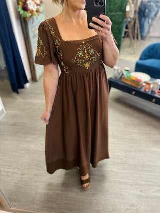 Woman wearing an embroidered floral midi dress with puff sleeves and square neckline, mirror selfie.