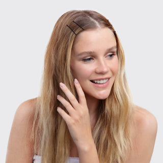 Young woman with blonde hair wearing black bobby pins while waving and smiling