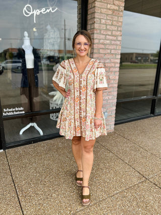Woman wearing VERY J Fall Feels Floral Mini Dress with platform sandals outside boutique storefront.
