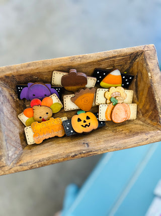 Wooden dough bowl filled with handmade fall and Halloween themed hair clips including pumpkins and bats.