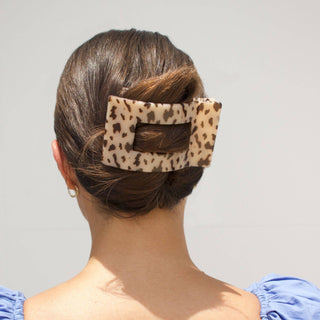 Woman wearing a tortoiseshell patterned rectangular hair clip in an elegant updo hairstyle from behind.