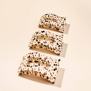 Three tortoiseshell hair clips with gold metal clasps arranged on a light background
