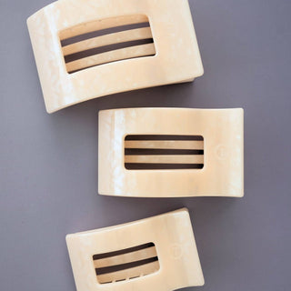 Three flat rectangular hair clips with striped cutout design on gray background