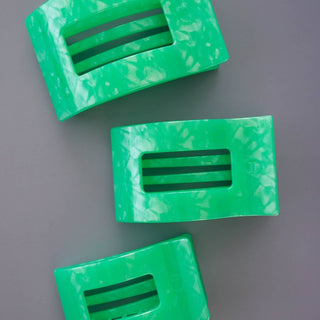 Three green marbled flat rectangle hair clips with slotted openings displayed on gray background