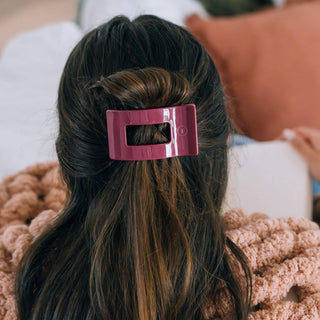 Woman wearing pink rectangular hair clip in brown hair with cozy sweater background