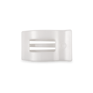 White rectangular hair clip with rounded corners and horizontal ridged texture on black surface