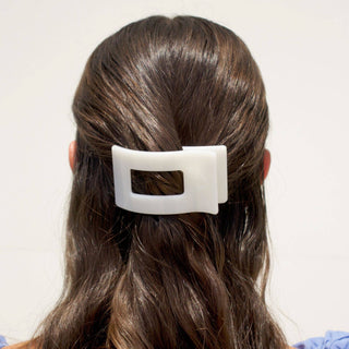 Back view of woman wearing white rectangular hair clip in brown wavy hair