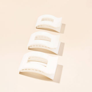 Three white rectangular hair clips with curved shape and cutout details on beige background